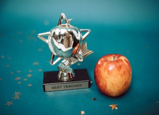 Silver star-shaped trophy with apple on a blue background for teacher appreciation.