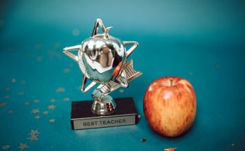Silver star-shaped trophy with apple on a blue background for teacher appreciation.