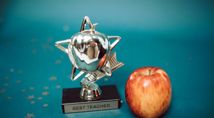 Silver star-shaped trophy with apple on a blue background for teacher appreciation.
