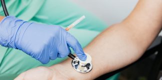 Healthcare professional using a stethoscope on patient's wrist during a medical exam.