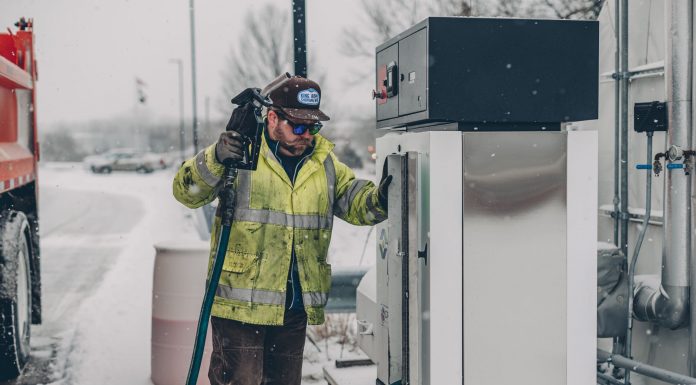 BREAKING: Strong Odor in Hoboken Traced to Gas Station Remediation A man wearing a jacket refuels a truck at a gas station during winter with snow falling.