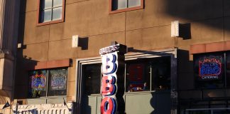 Neon signage of Dallas BBQ Restaurant illuminated in an urban environment at sunset.