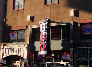 Neon signage of Dallas BBQ Restaurant illuminated in an urban environment at sunset.