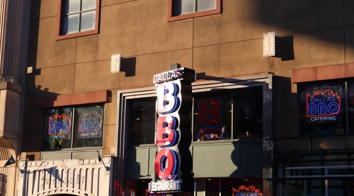 Neon signage of Dallas BBQ Restaurant illuminated in an urban environment at sunset.