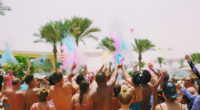 A lively outdoor Holi celebration on the beach with colorful powder and a joyful crowd.