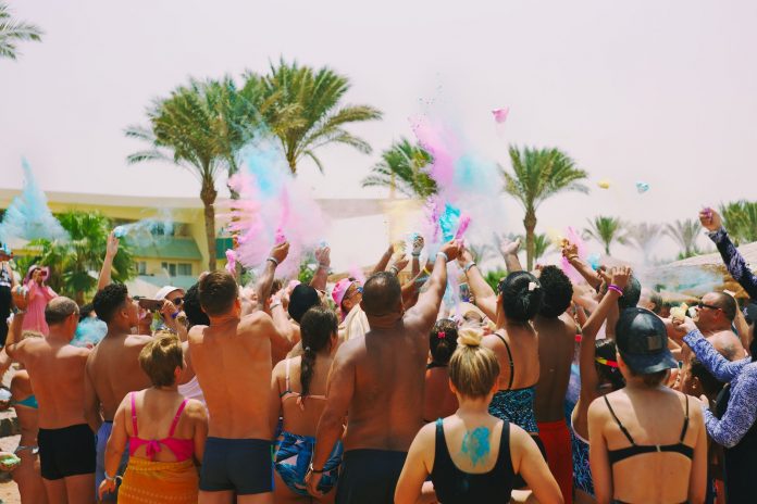 breaking-vibrant-weekend-events-set-for-jersey-cit A lively outdoor Holi celebration on the beach with colorful powder and a joyful crowd.