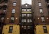 Low-angle view of urban brick apartment buildings with fire escapes, embodying classic city architecture.