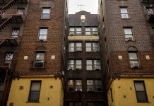 Low-angle view of urban brick apartment buildings with fire escapes, embodying classic city architecture.