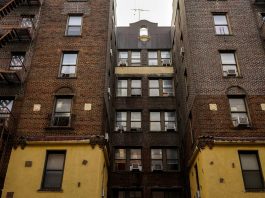 Low-angle view of urban brick apartment buildings with fire escapes, embodying classic city architecture.