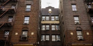 Low-angle view of urban brick apartment buildings with fire escapes, embodying classic city architecture.