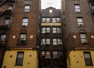 Low-angle view of urban brick apartment buildings with fire escapes, embodying classic city architecture.