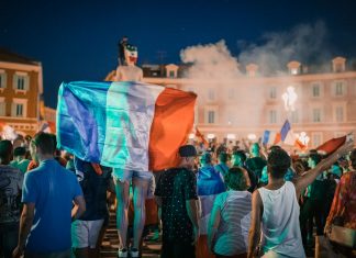 Central Avenue Plans Big World Cup Weekend Celebration in July Vivid night-time celebration in France with crowds waving flags in city square.