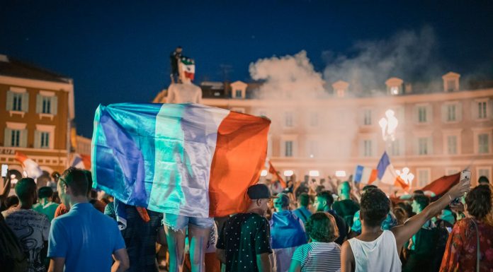 Central Avenue Plans Big World Cup Weekend Celebration in July Vivid night-time celebration in France with crowds waving flags in city square.