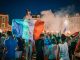 Central Avenue Plans Big World Cup Weekend Celebration in July Vivid night-time celebration in France with crowds waving flags in city square.
