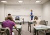 A college educator proctoring an exam, enforcing no cheating rules.