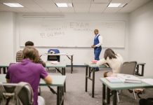 A college educator proctoring an exam, enforcing no cheating rules.