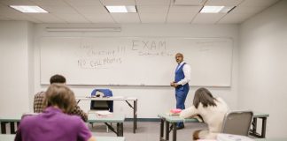 A college educator proctoring an exam, enforcing no cheating rules.