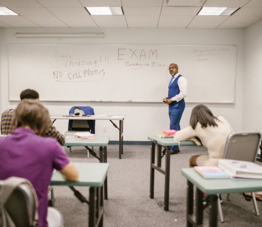 A college educator proctoring an exam, enforcing no cheating rules.