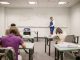 A college educator proctoring an exam, enforcing no cheating rules.
