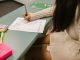 Student secretly looking at a cheat sheet under the desk while taking an exam in a classroom setting.