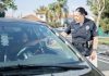 A police officer hands a traffic ticket to a driver in a parked car. Public safety interaction.