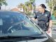 A police officer hands a traffic ticket to a driver in a parked car. Public safety interaction.