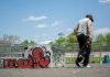 Cosas Gratis Que Hacer en Union City en 2026: Diversión Sin Gastar un Dólar Man with skateboard at urban skatepark, Clifton NJ. Vibrant graffiti art.