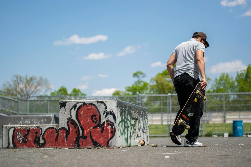 Man with skateboard at urban skatepark, Clifton NJ. Vibrant graffiti art.