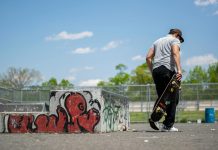 Man with skateboard at urban skatepark, Clifton NJ. Vibrant graffiti art.