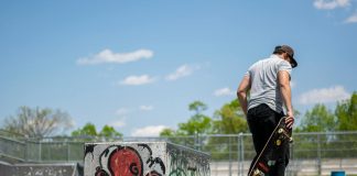 Man with skateboard at urban skatepark, Clifton NJ. Vibrant graffiti art.