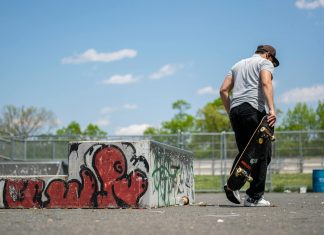 Man with skateboard at urban skatepark, Clifton NJ. Vibrant graffiti art.