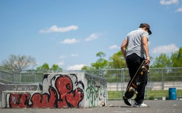 Man with skateboard at urban skatepark, Clifton NJ. Vibrant graffiti art.