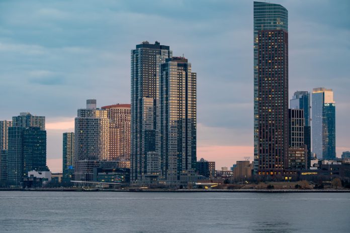 Twilight view of the iconic New York City skyline with skyscrapers and tranquil waters.