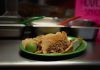 Close-up of delicious tacos with meat and lime, served on a green plate in a Mexican eatery.