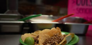 Close-up of delicious tacos with meat and lime, served on a green plate in a Mexican eatery.