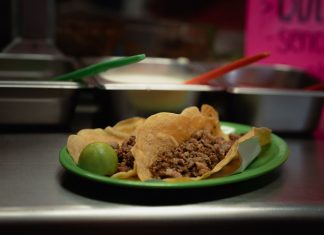Close-up of delicious tacos with meat and lime, served on a green plate in a Mexican eatery.