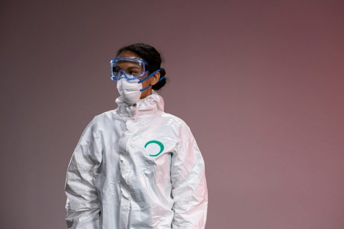 ebola-outbreak-far-away-but-cdc-watching-closely-h Medical professional in full protective suit with goggles and mask, studio setting.