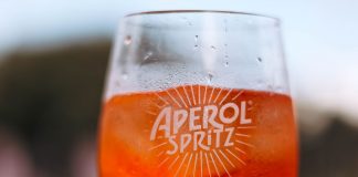 Refreshing Aperol Spritz cocktail on a sunny day with a blurred outdoor background.