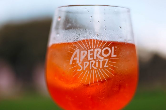 elizabeth-s-new-italian-spot-has-an-aperol-spritz- Refreshing Aperol Spritz cocktail on a sunny day with a blurred outdoor background.