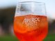 Refreshing Aperol Spritz cocktail on a sunny day with a blurred outdoor background.