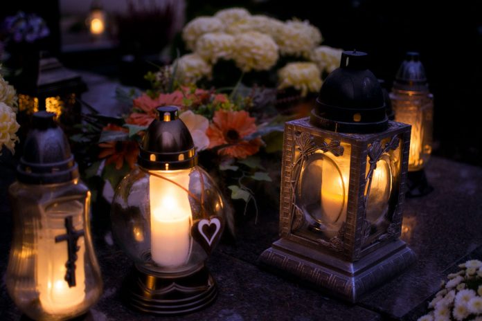 elizabeth-says-goodbye-to-cinthia-d-remedios-gonza Lanterns with candles illuminate a cemetery on All Saints' Day.