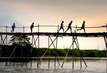 Film Screening in Jersey City Tells the Story of Teenage Migrants Unrecognizable active ethnic kids jogging on footbridge above lake while working out under sunset sky