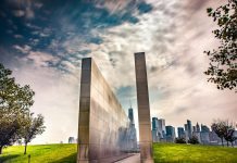 Stunning reflection memorial with New York City skyline in the background under a dynamic sky.