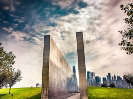 Stunning reflection memorial with New York City skyline in the background under a dynamic sky.