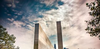 Stunning reflection memorial with New York City skyline in the background under a dynamic sky.
