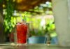 A vibrant strawberry cocktail with pineapple garnish on an outdoor table in sunny garden.