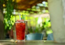 A vibrant strawberry cocktail with pineapple garnish on an outdoor table in sunny garden.
