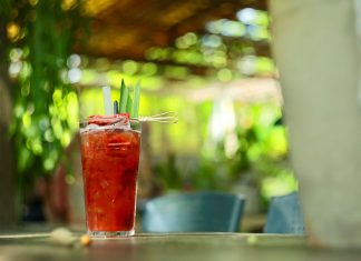 A vibrant strawberry cocktail with pineapple garnish on an outdoor table in sunny garden.