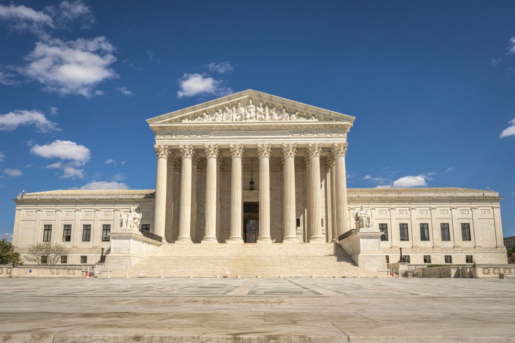 The majestic facade of the United States Supreme Court under a clear blue sky.