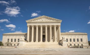 The majestic facade of the United States Supreme Court under a clear blue sky.